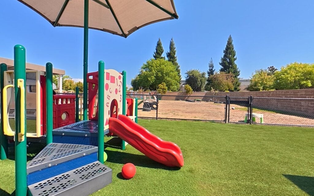 Outdoor playground with slide and turf at Kids Inc. Preschool