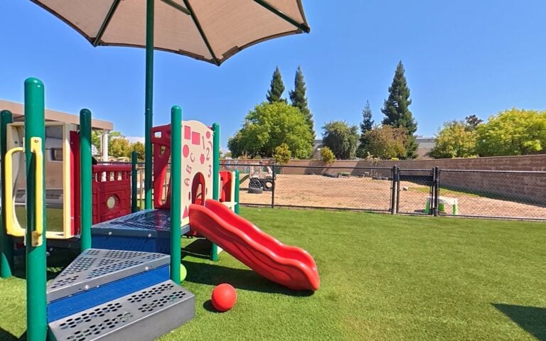 Outdoor playground with slide and turf at Kids Inc. Preschool